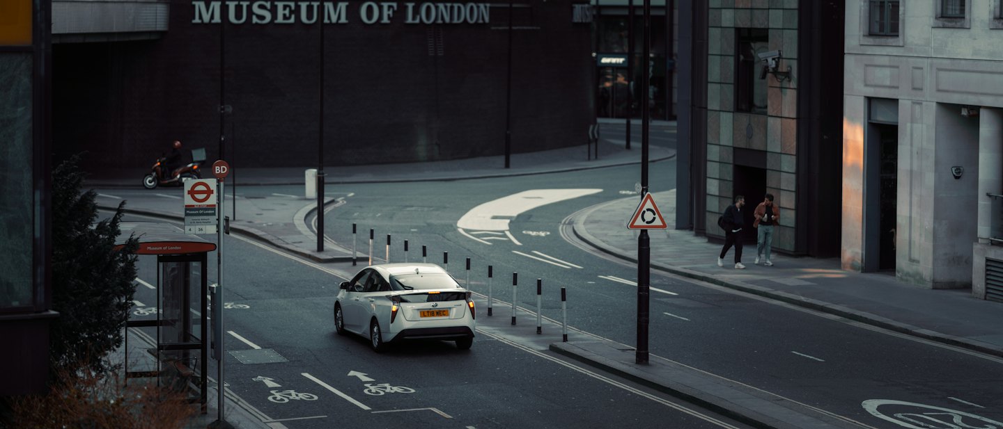 Vehicles and pedestrians move along a London street near the museum.