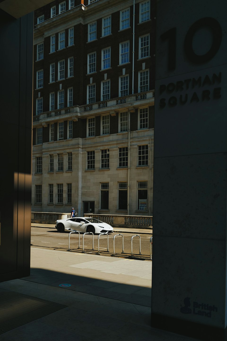 White sports car parked by bicycle racks on a sunny day.