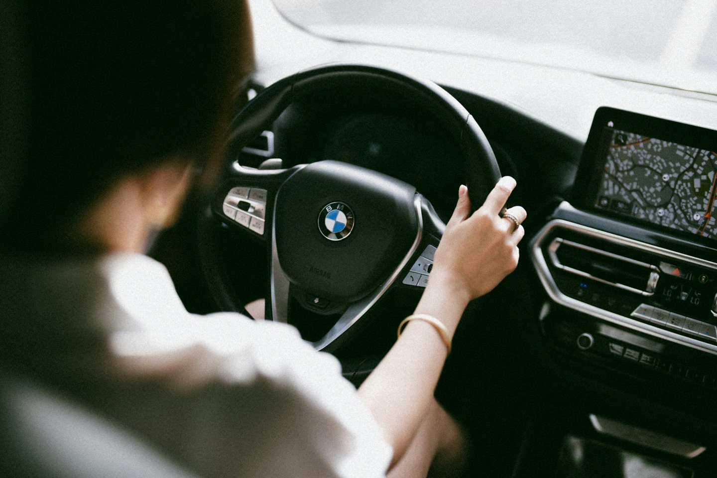 Person's hand on a car's steering wheel, map on dashboard.