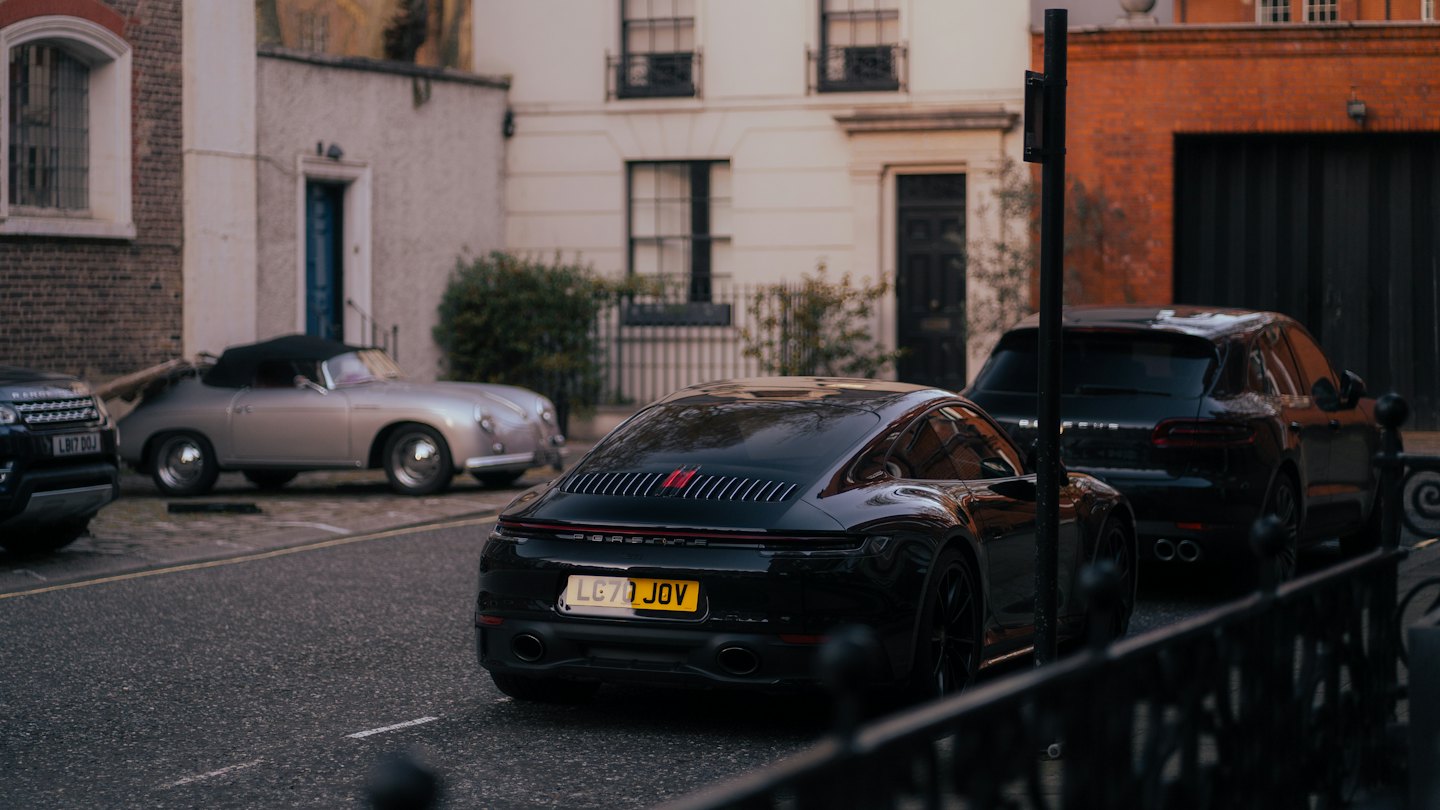 Luxury cars parked along a quiet residential street.